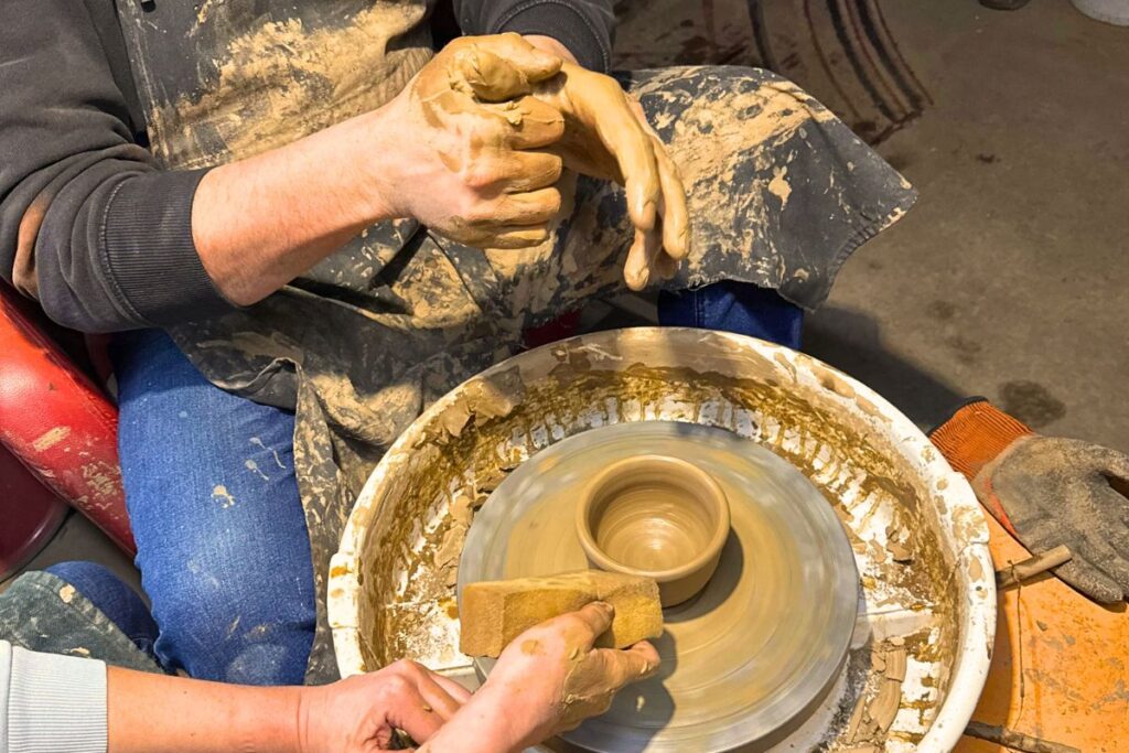 Nauczyciel pokazuje jak pracować w warsztacie ceramiki w Czarnej Wsi Kościelnej podczas wycieczki Podlaski Reset