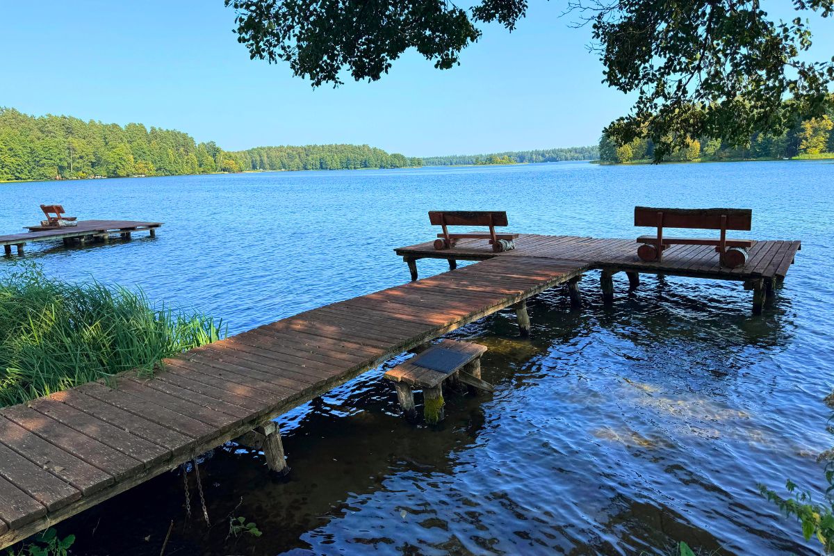 Dwie drewniane ławki nad brzegiem jeziora w Augustowie – idealne miejsce na odpoczynek w rytmie slow podczas Podlaskiego Resetu.