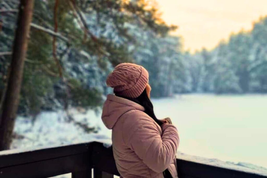 Turystka nad zamarzniętym jeziorem Suchar w Wigierskim Parku Narodowym zimą – aktywny odpoczynek na Suwalszczyźnie.