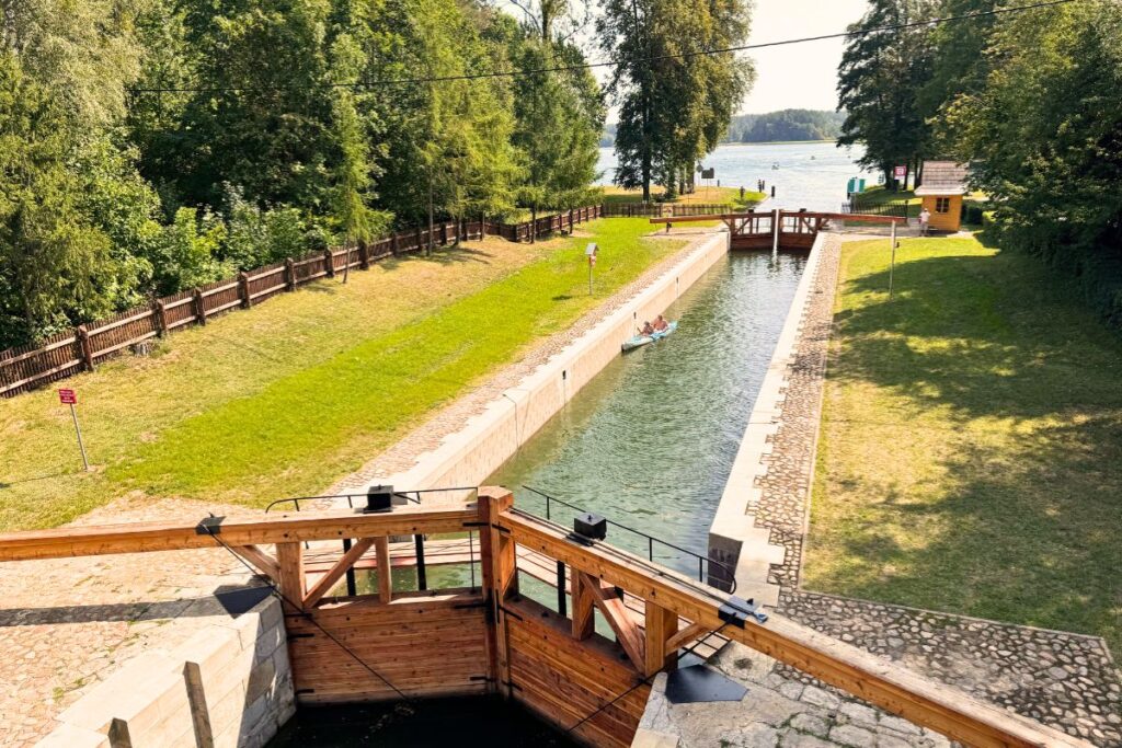 Kajakarz przepływający przez zabytkową śluzę Przewięź na Kanale Augustowskim – aktywna regeneracja na wodzie.